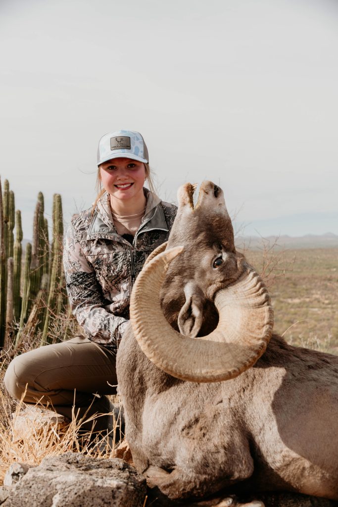Female hunter with desert bighorn sheep trophy in Mexican desert cactus landscape documented by Wildsmith videography