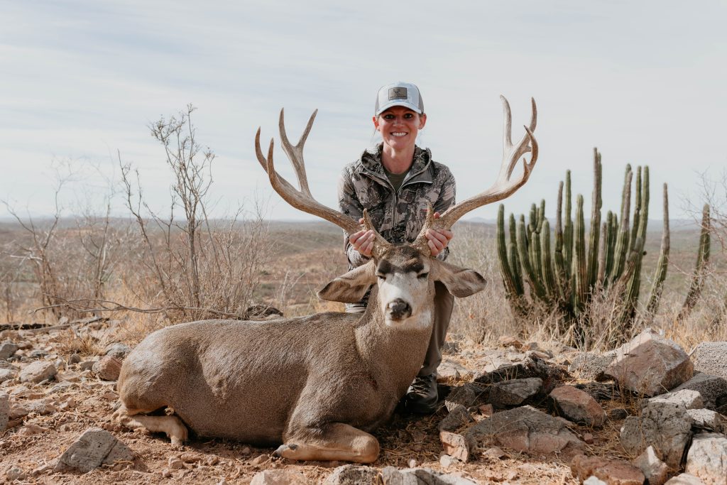 Female hunter with trophy mule deer buck in Mexican desert landscape with saguaro cacti documented by Wildsmith videography