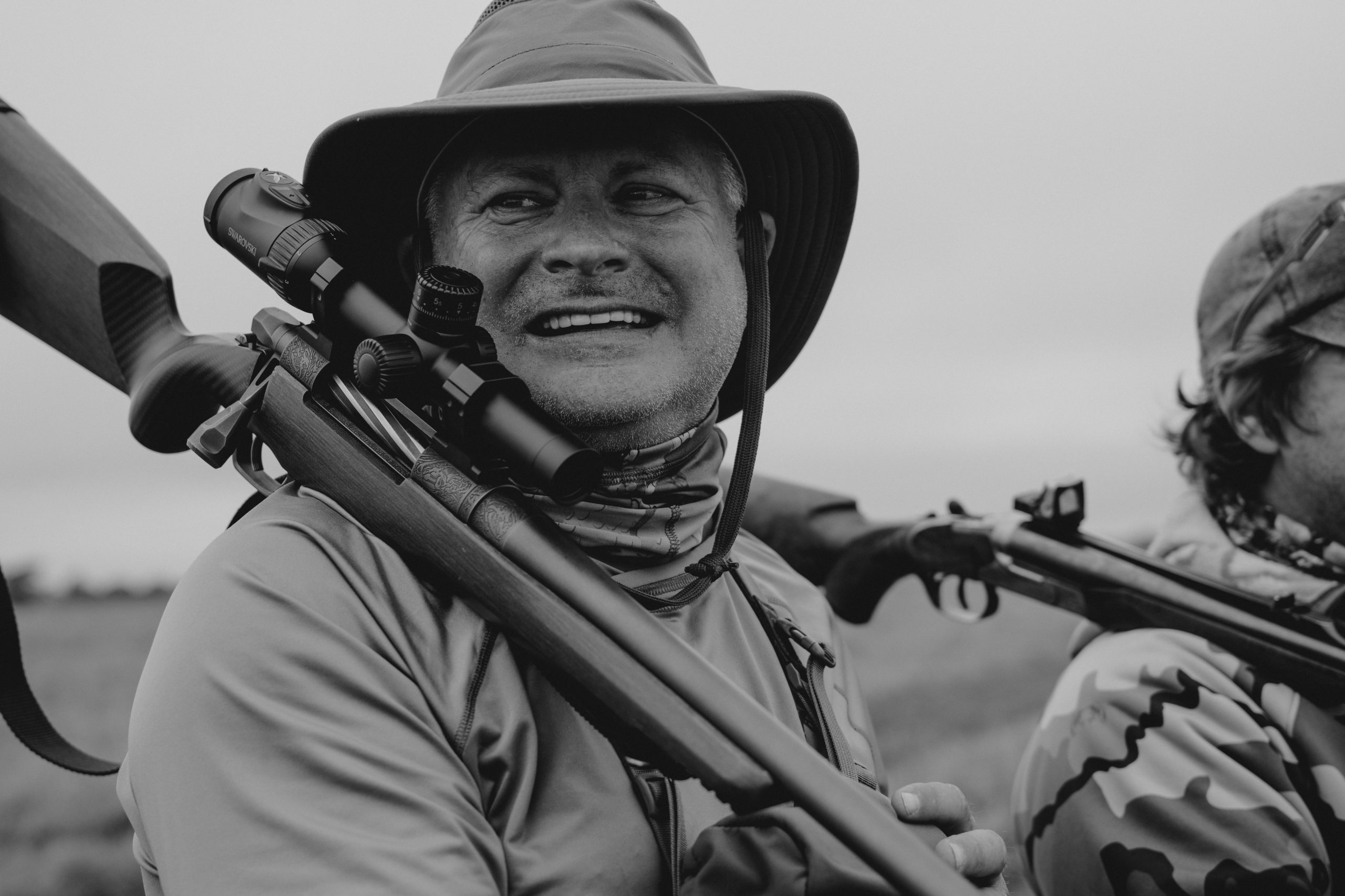 Happy hunter with scoped rifle celebrating successful South African safari hunt documented by Wildsmith videography team