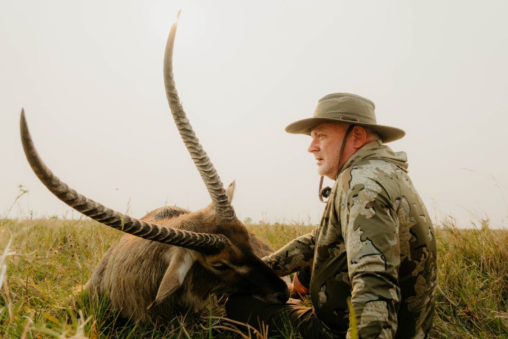 Hunter with trophy waterbuck displaying impressive spiral horns in South African grasslands documented by Wildsmith safari videography