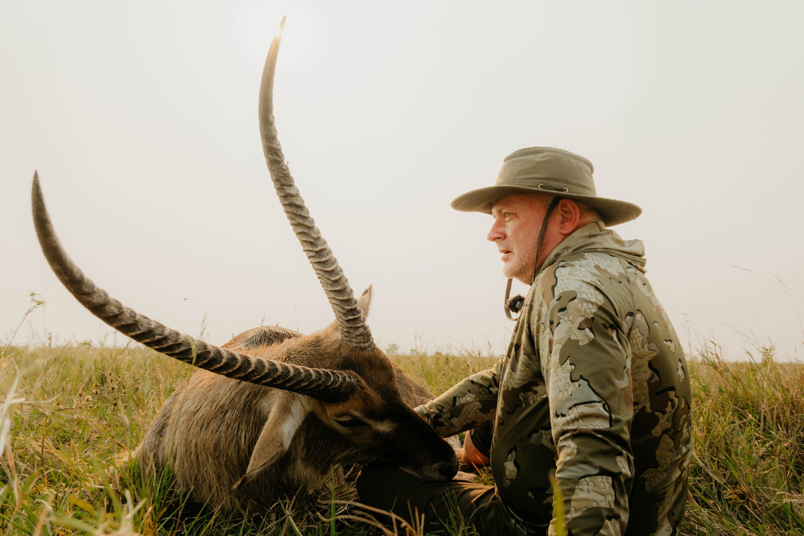 Hunter with trophy waterbuck displaying impressive spiral horns in South African grasslands documented by Wildsmith safari videography