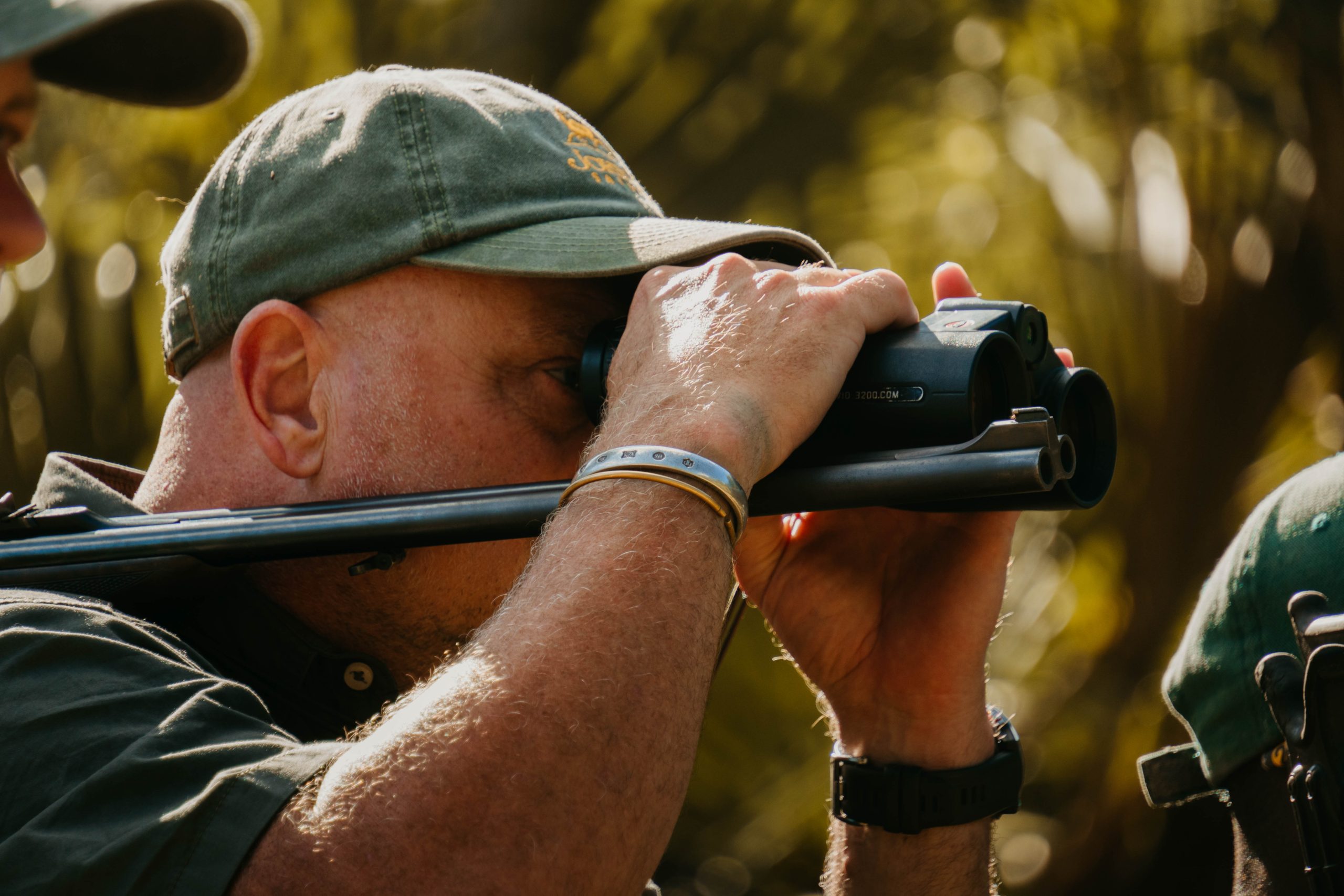 Professional hunter aiming rifle with scope in golden hour light during African safari hunt