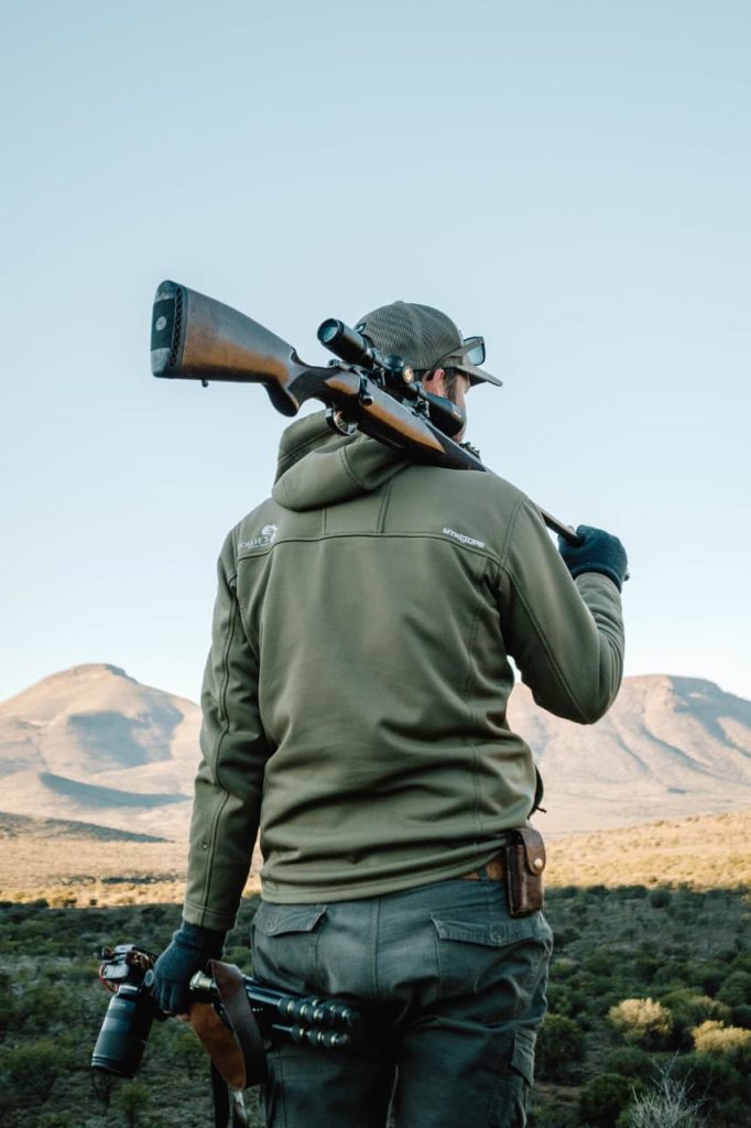 Michael from Wildsmith with scoped rifle and professional camera equipment in South African hunting terrain
